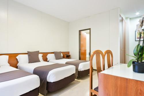 a hotel room with three beds and a table at Hotel Condal in Barcelona