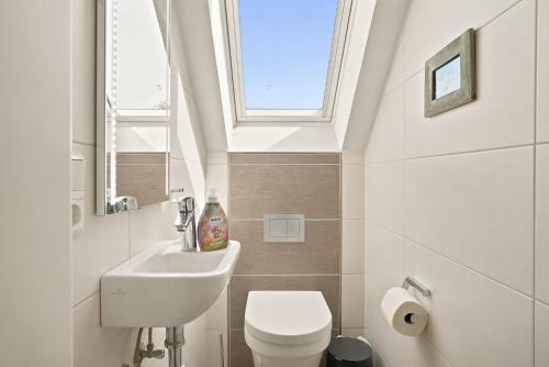 a bathroom with a sink and a toilet and a window at Amelie in Greetsiel