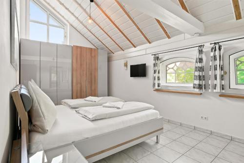 a white bedroom with a bed and a window at Villa Aurum in Greetsiel