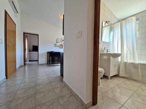a white bathroom with a toilet and a sink at Apartments Rosa Soldatica in Vir