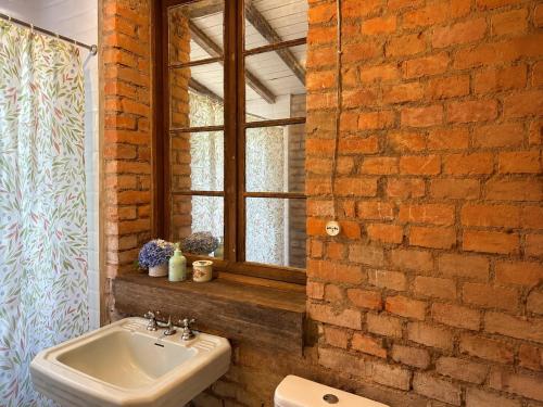 a bathroom with a sink and a brick wall at Piccola Cucina: Casa centenária Vale dos Vinhedos in Garibaldi