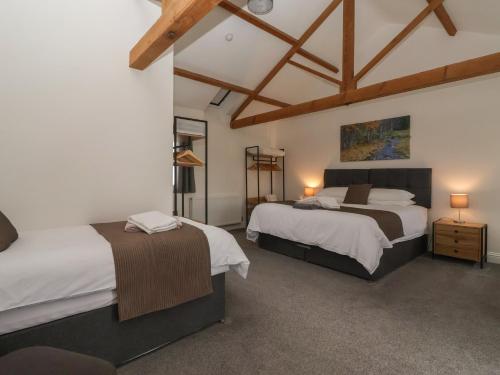 two beds in a room with white walls and wooden ceilings at Miller's Wheel in Harrogate