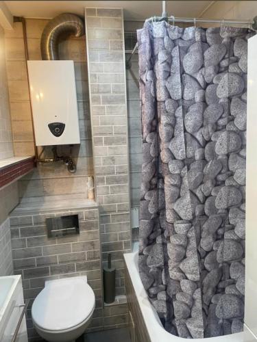 a bathroom with a toilet and a shower curtain at Second&Home 3 in Kalisz