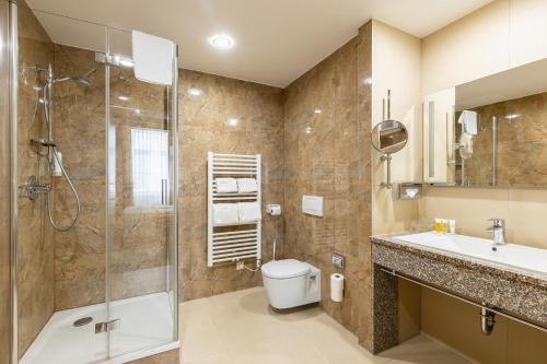 a bathroom with a shower and a toilet and a sink at HiLight Suites Hotel in Vienna