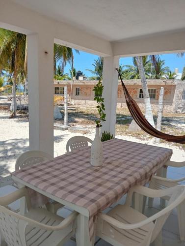 a table and chairs on a porch with a hammock at Cozy beachfront house Cocomar in San Crisanto
