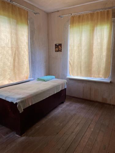 a small bedroom with a bed and two windows at Lake View Sioni in Sioni