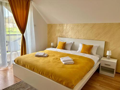 a bedroom with a large bed with a yellow blanket at Vila Safir MM in Şurdeşti