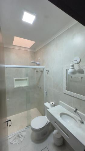 a bathroom with a shower and a toilet and a sink at Hotel Casarão Pitangueiras in Guarujá