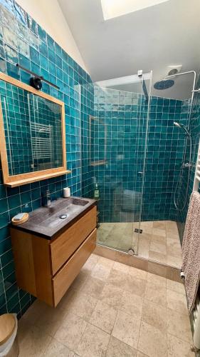 a blue tiled bathroom with a sink and a shower at L'Autre Paradis-Piscines naturelles-Plages-Jardin enchanté-Sauna in Poligny