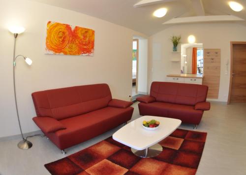 a living room with two red couches and a table at Karglhof Villa in Faak am See