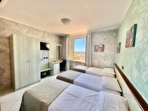 una camera da letto con tre letti e una finestra di Albergo Posta a Genova