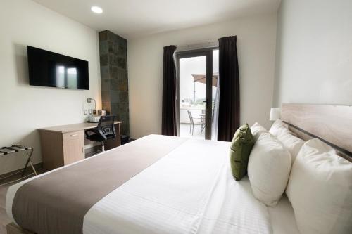 a bedroom with a large white bed and a desk at Hotel EJM PREMIUM in Irapuato