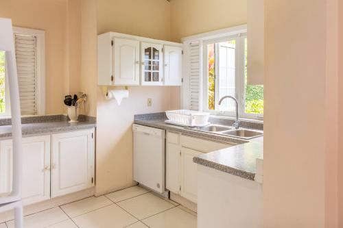 a kitchen with white cabinets and a sink at Plantation Beach Villas in Black Rock