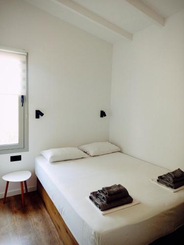 a white bedroom with a bed and a chair at Agave by Aloe Residence Possidi in Possidi