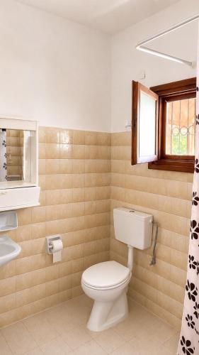 a bathroom with a toilet and a sink and a window at Gian Petro Apartments in Sidari