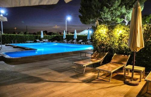 a swimming pool at night with chairs and an umbrella at GLAMPING by SUNBEAM in Leporano Marina
