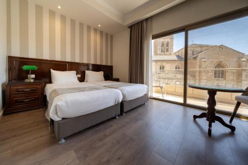 a bedroom with two beds and a table and a window at Christmas Hotel - Jerusalem in Jerusalem