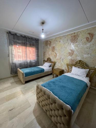 a bedroom with two beds with blue sheets at Appartement cozy in Oujda