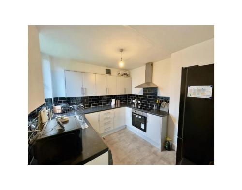 a kitchen with a black refrigerator and white cabinets at Wunderschönes Chalet in Oberstdorf mit Berg in Oberstdorf
