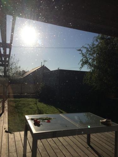 a glass table on a deck with the sun in the background at Chambres d'hôtes de Cécile in Notre-Dame-dʼAllençon