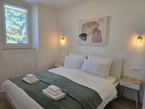 a white bedroom with a bed with towels on it at Villa 1902 Omišalj in Omišalj