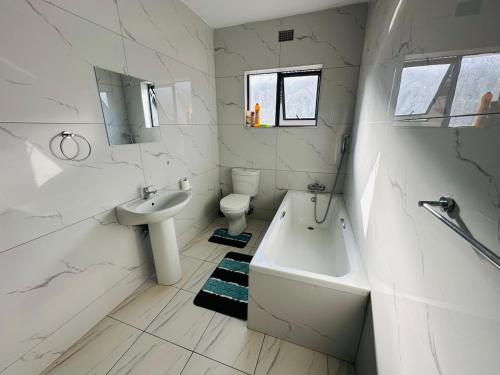 ein weißes Badezimmer mit Waschbecken, Badewanne und Toilette in der Unterkunft SimPhil Haven in Bulawayo