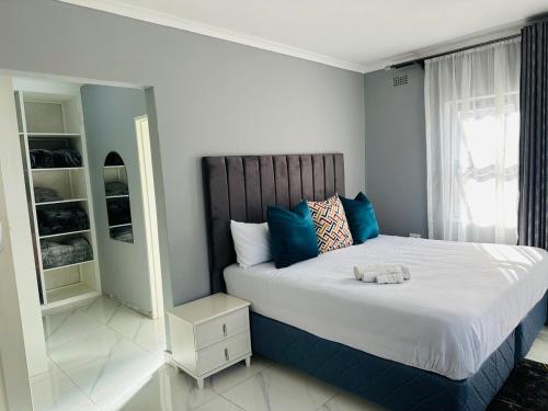 ein Schlafzimmer mit einem großen Bett und blauen Kissen in der Unterkunft SimPhil Haven in Bulawayo