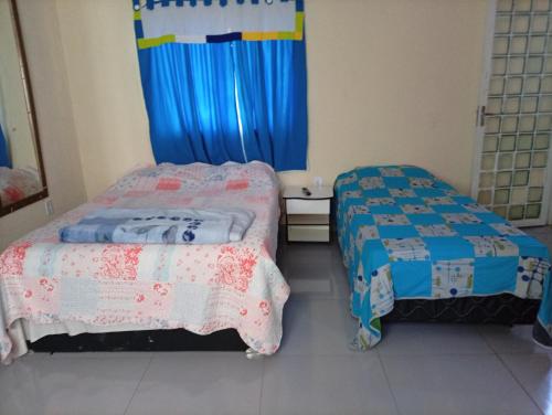 two beds in a small room with blue curtains at Hospedagem da Fran in Brasília
