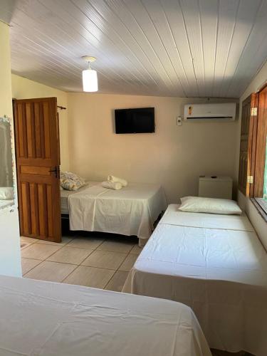 a room with two beds and a flat screen tv at Pousada Orienttal in Santarém