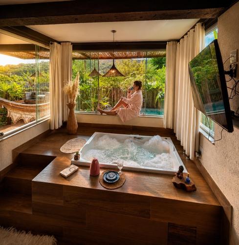 a man in a bath tub in a room with a window at Loft Mandalua in Serra do Cipo