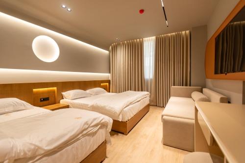 a hotel room with two beds and a couch at Hotel Berfin in Vlorë