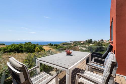 a table and chairs on a deck with a view of the ocean at Villa Panorama Kalathas - 4 Bedrooms Near beach in Chorafakia