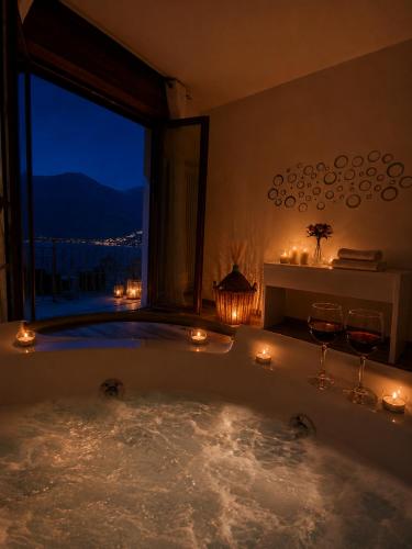 a bath tub with candles in a room with a window at Dudi Jolie Maison - Jacuzzi in Lezzeno