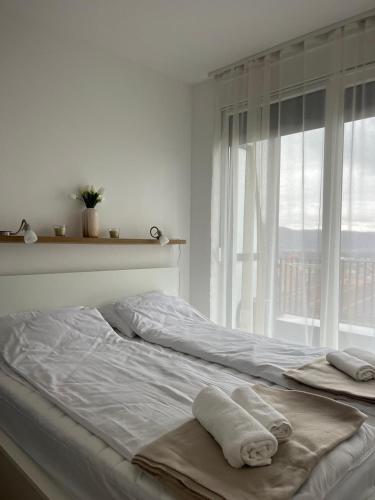 a white bedroom with two towels on a bed at Porodična oaza Vrnjačka Banja in Vrnjačka Banja