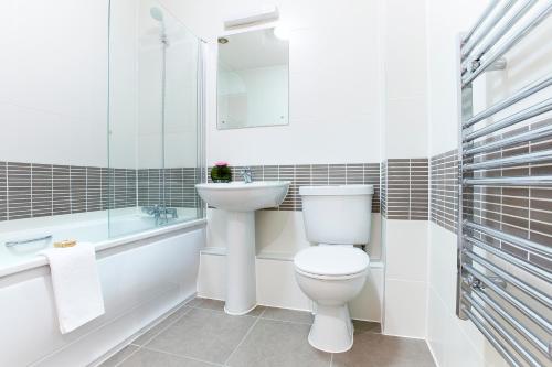 a white bathroom with a toilet and a sink at Watford Centre - Spacious Penthouse in Watford