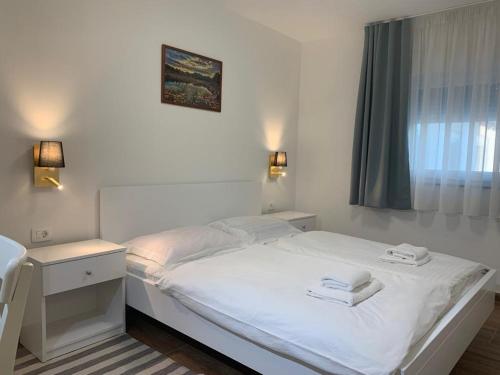 a white bed in a room with a window at Apartmani Albatros in Perušić
