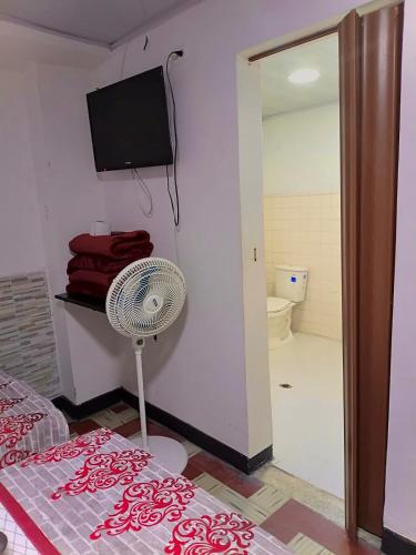 a room with a fan and a bathroom with a toilet at Hotel Bachue Ibagué in Ibagué