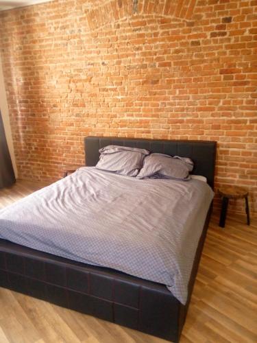 a bed in a room with a brick wall at TG Krakowska Kamienica in Tarnowskie Góry