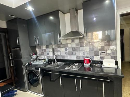 a kitchen with black cabinets and a sink and a stove at JULYA appartement centre in Tangier