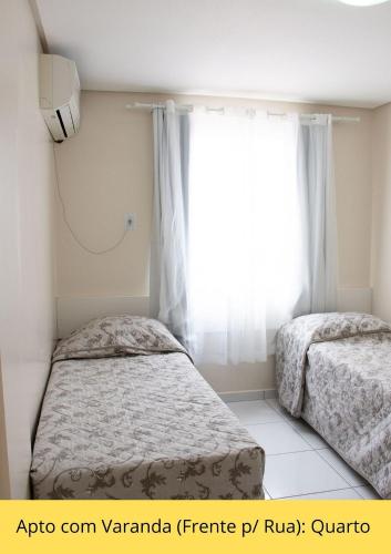 two beds in a room with a window at Residencial Dona Naime in Bombinhas