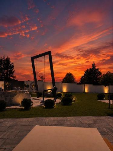a sunset in a park with a sculpture in the grass at Villa Prestiž in Sokolac
