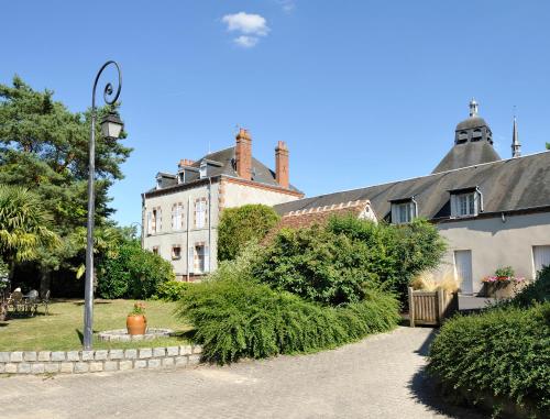 an old house with a large building in the background at Logis Hôtel Restaurant Du Labrador in Saint-Benoît-sur-Loire