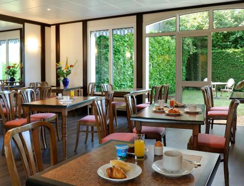 een restaurant met tafels, stoelen en ramen bij Hôtel Du Labrador in Saint-Benoît-sur-Loire