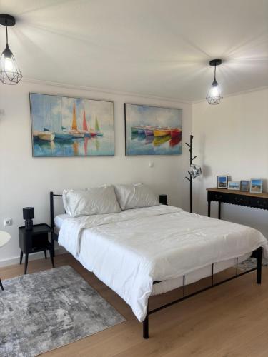a bedroom with a white bed and paintings on the wall at Yialos Kalamos in Kalamos