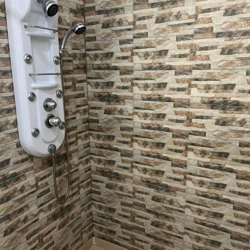 a shower in a bathroom with a brick wall at La Villa Fleur d'Edene in Abidjan