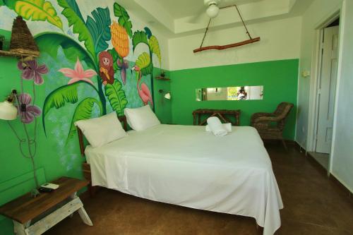 a bedroom with a white bed and a colorful wall at Bayahibe Essentials Rooms in Bayahibe