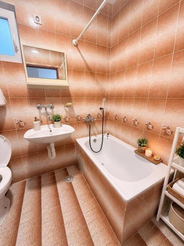 a bathroom with a tub and a toilet and a sink at Central Nesst Budva in Budva