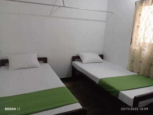 two beds in a room with green and white at Nimansala Eco Resort in Parakaduwa