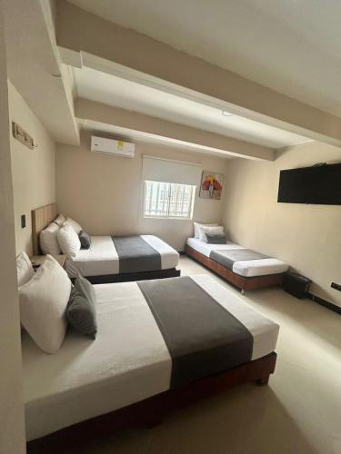 a bedroom with three beds and a flat screen tv at Hotel Villa Real 70 Laureles in Medellín