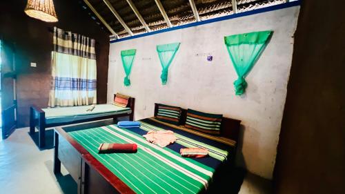 a bedroom with a bed with green sheets and pillows at Hakuna Matata Hostel in Sigiriya